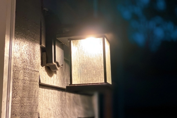 Eine eingeschaltete Außenleuchte an einer Hauswand